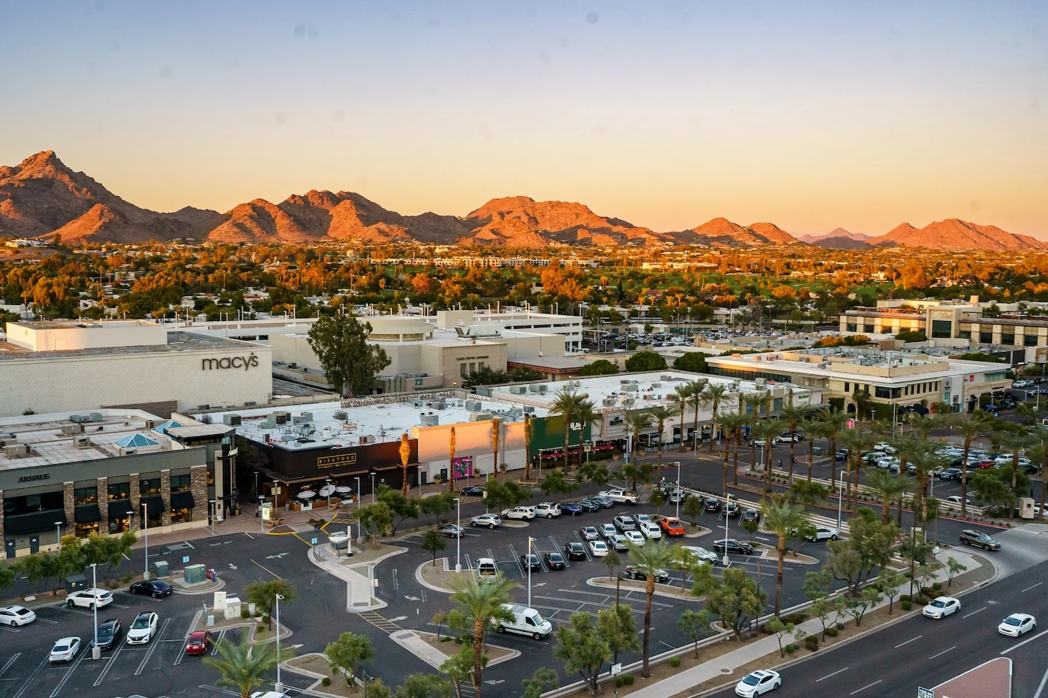 Elevated view of Biltmore Fashion Park, with palm-lined shops and Phoenix mountains in warm evening light