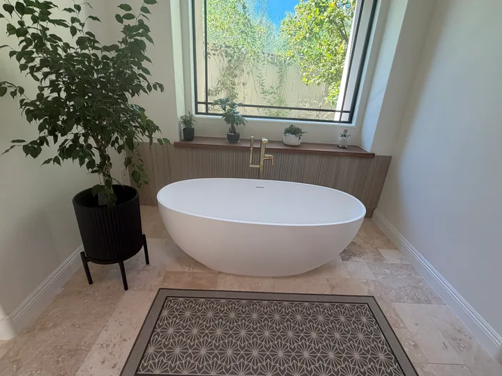 Freestanding soaking tub on a stone floor below a garden window after a Greater Phoenix Cleaning standard clean