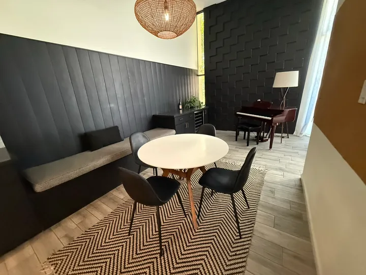 Dining nook with a round white table, black paneled walls and a woven pendant light after a Greater Phoenix Cleaning deep clean