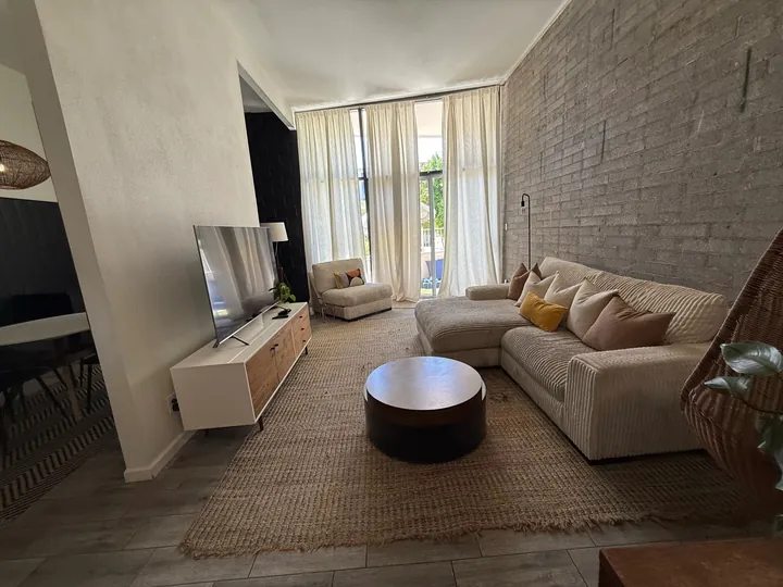 Living room with a cream sectional, a jute rug and a brick accent wall after a Greater Phoenix Cleaning deep clean